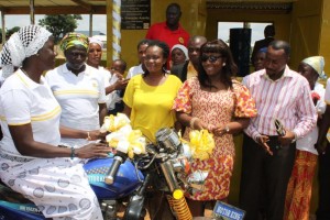 MRS FIAGBENU HANDING OVER THE KEYS TO THE TRICYCLE TO A MEMBER OF SUNG SUMA WOMEN GROUP